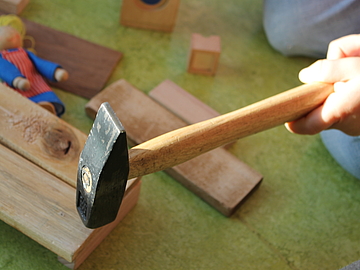 Mit dem passenden Werkzeug bauen die Kinder gemeinsam mit ihren Erzieherinnen und Erziehern ein Puppenhaus aus Holz